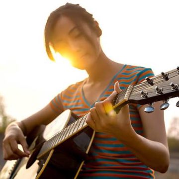 young-womans-hand-playing-guitar-outdoors