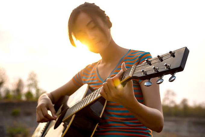 young-womans-hand-playing-guitar-outdoors